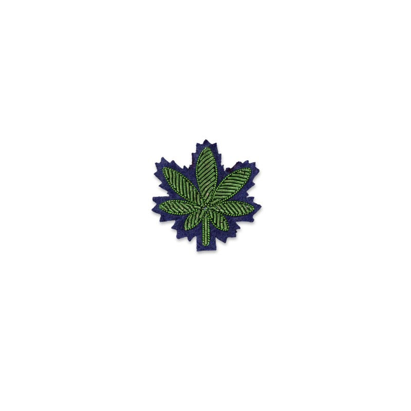 Broche brodée à la main de Macon & Lesquoy représentant une feuille de cannabis, coloris vert sur fond bleu. Dimensions : 3x3,2cm
