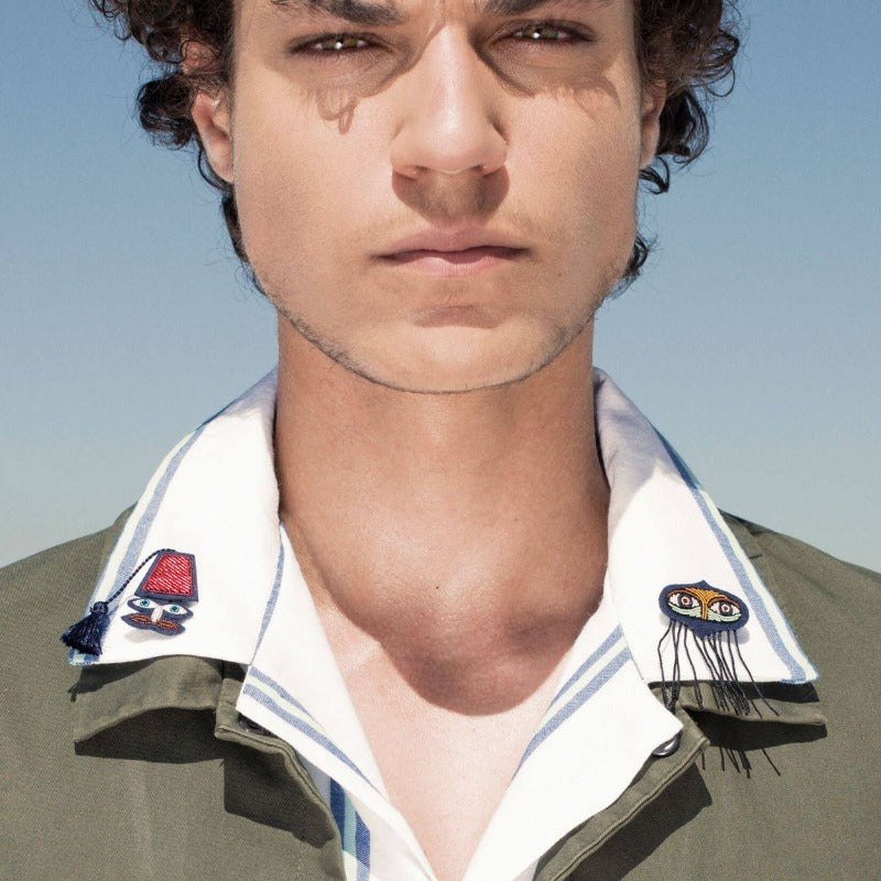 Broche sur un col de chemise blanche.
