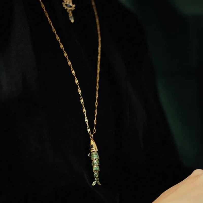 Collier Sacha poisson articulé avec yeux émaillés et les écailles émaillées en bleu transparent. Laiton bain d’or. Longueur de la chaîne 55 cm, longueur du poisson 4 cm.