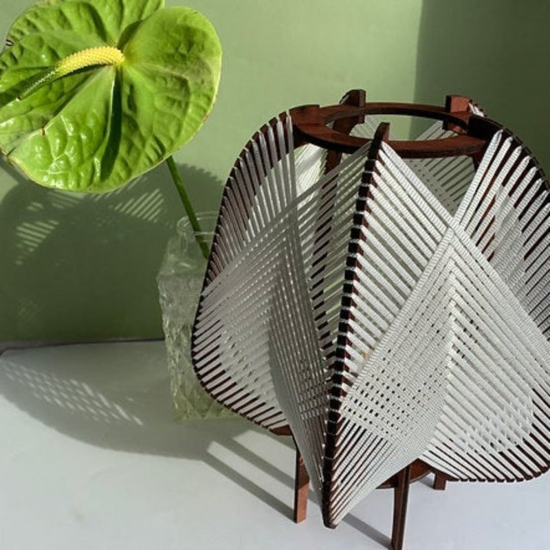 Lampe à poser modèle Otta de l'Atelier Mathilde Louise. Ossature de la lampe en bois teinté teck et tissage gris clair.