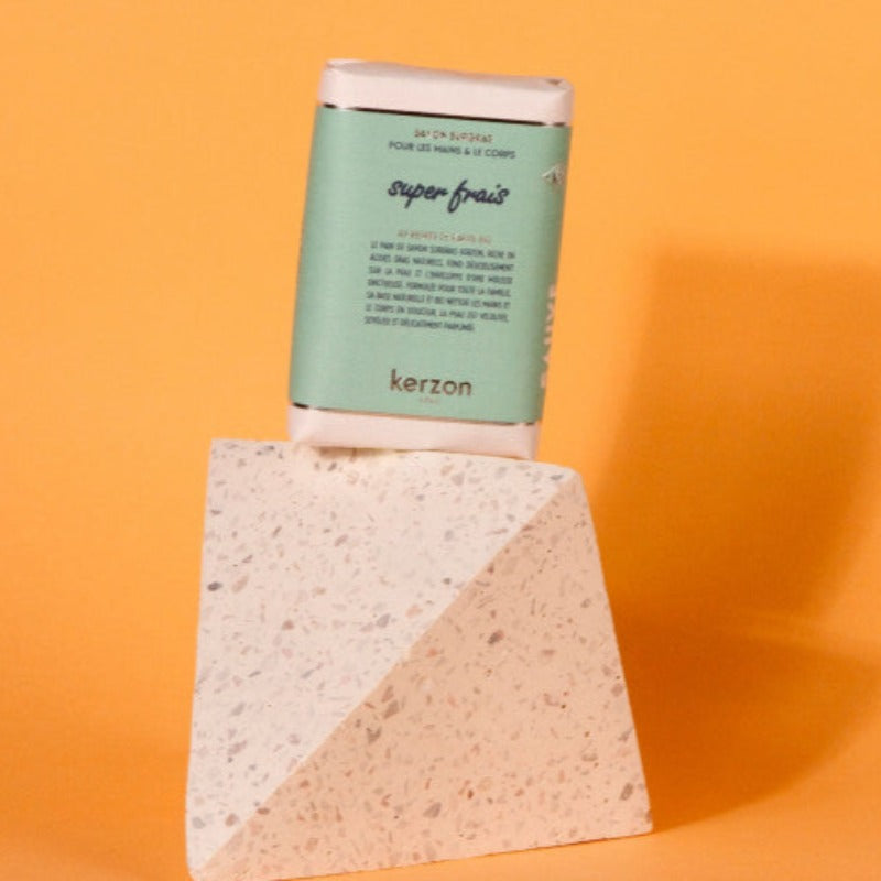 Le pain de savon surgras Kerzon, enrichi en beurre de karité bio et formulé pour toute la famille, nettoie les mains et le corps en douceur. Douceur de l'enfance, Super Frais ravive le souvenir des parfums de bébé et le plaisir de s'envelopper dans des draps fraîchement lavés, avec une tête hespéridée légèrement anisée et un cœur chèvrefeuille, sur un fond cèdre et ylang. L’assemblage olfactif : cèdre & ylang