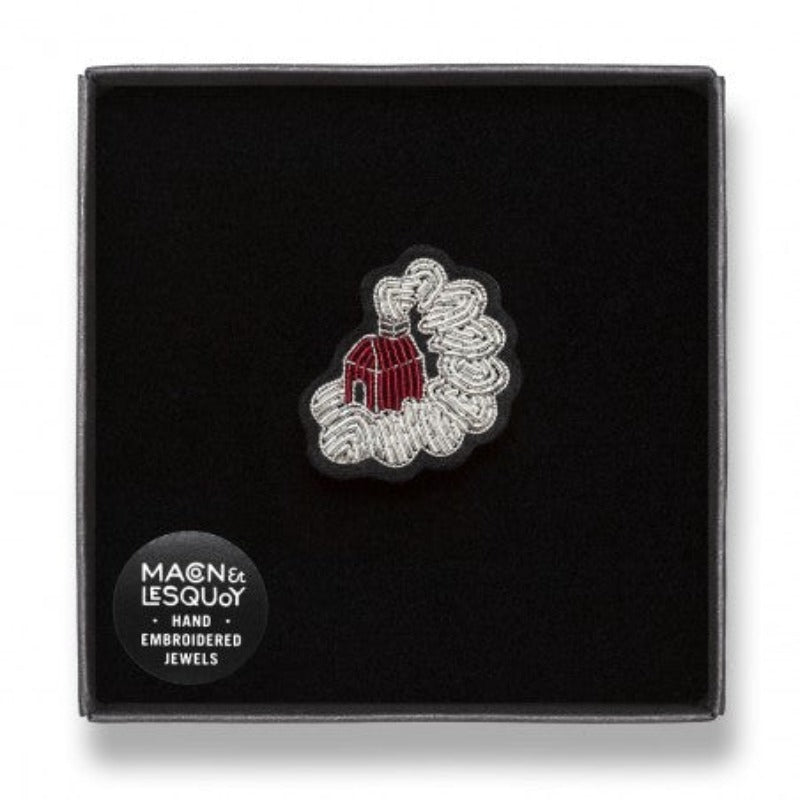 Broche brodee main en fil de cannetille de la marque Macon & Lesquoy. Paradis Blanc, maison rouge entouré par un nuage de fumée argentée. Dimensions : 2,9 x 3,1 cm. Broche présenté dans son écrin de velours noir.