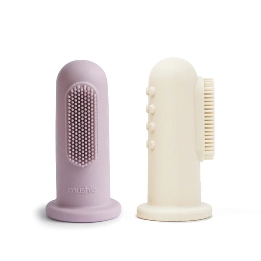 Lot de 2 brosses à dents au doigt Mushie. Coloris : lilas et ivoire. En silicone. 2 faces une face avec des poils pour laver, une face avec des petites bosses pour soulager.