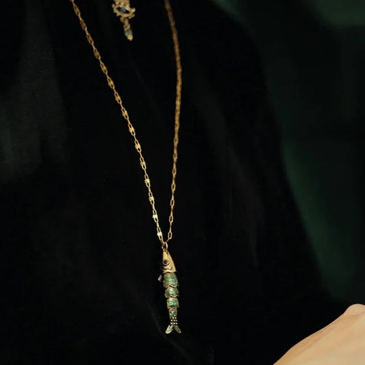 Collier Sacha poisson articulé avec yeux émaillés et les écailles émaillées en bleu transparent. Laiton bain d’or. Longueur de la chaîne 55 cm, longueur du poisson 4 cm.