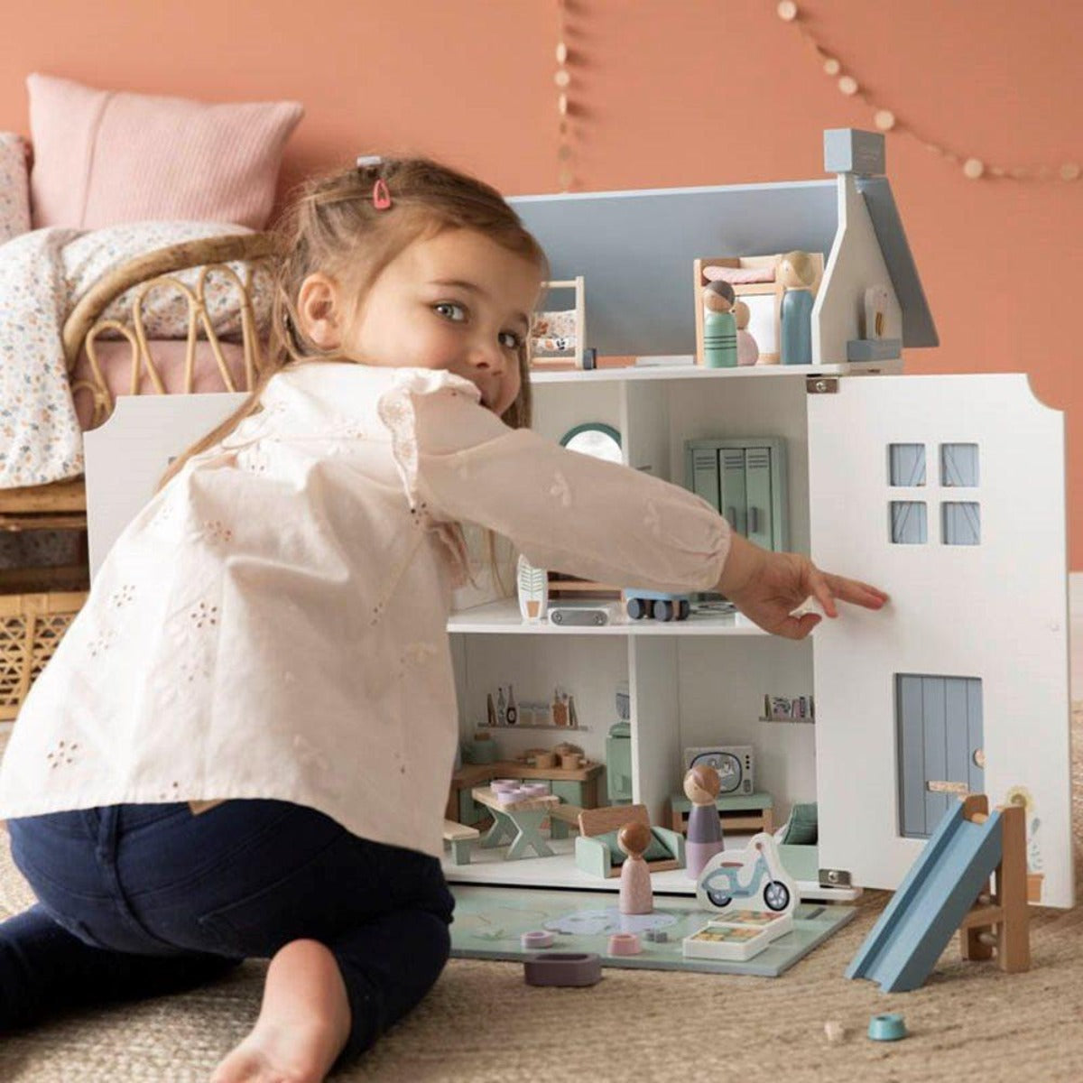 Petite fille jouant avec sa maison de poupée Little dutch et les extensions pour remplir chaque pièce de la maison.